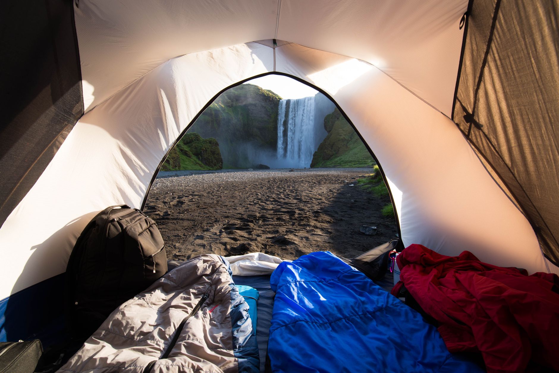 Compact tent, sleeping bag, and emergency blanket set up in a forest.
