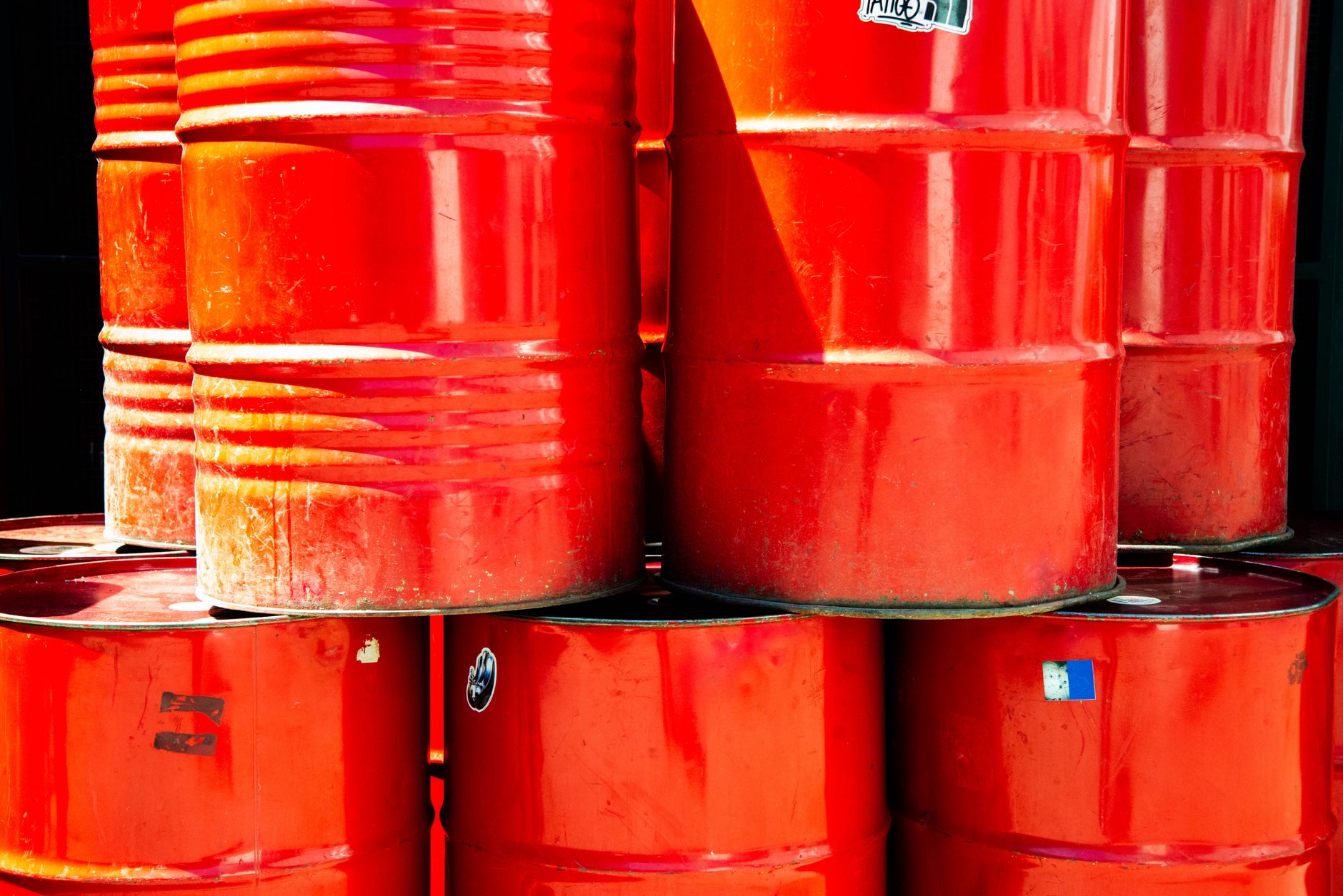 Blue plastic 55-gallon drums stacked horizontally in a basement for emergency water storage