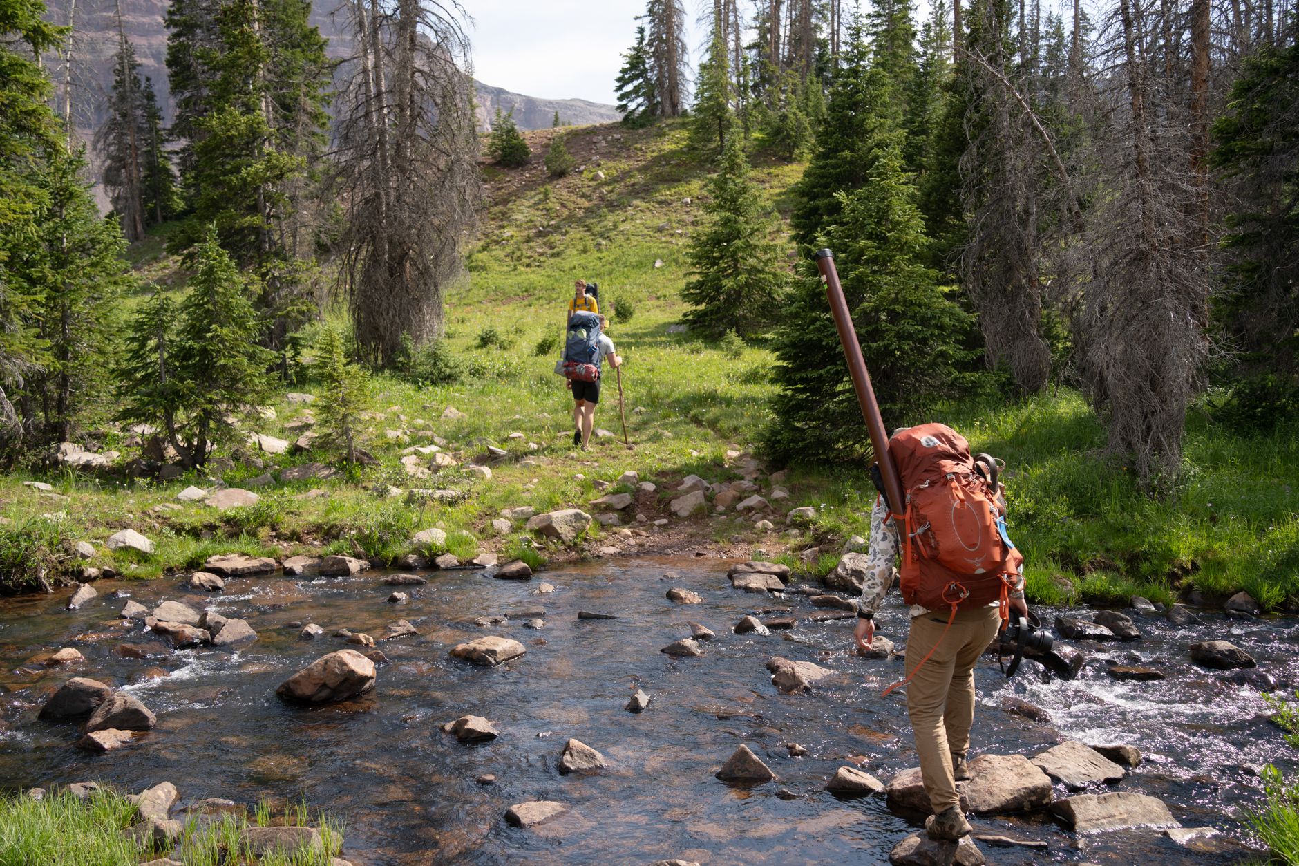 Hiker using a portable water filter to drink from a stream