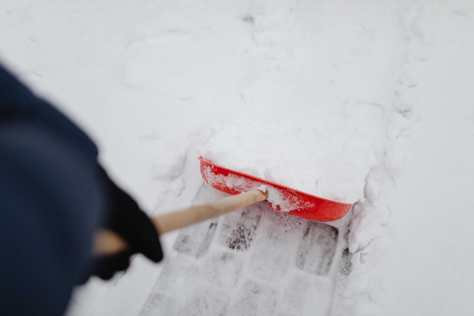 A passenger wearing warm clothing and covered with a blanket inside a car during a winter storm